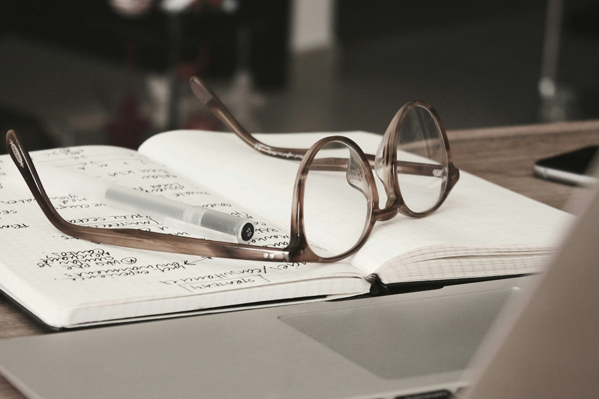 Pair of glasses sitting on top of a notebook